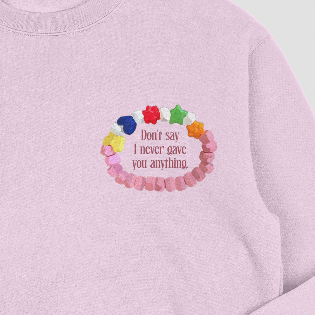 Pink sweatshirt with colorful bead design and text on a light gray background