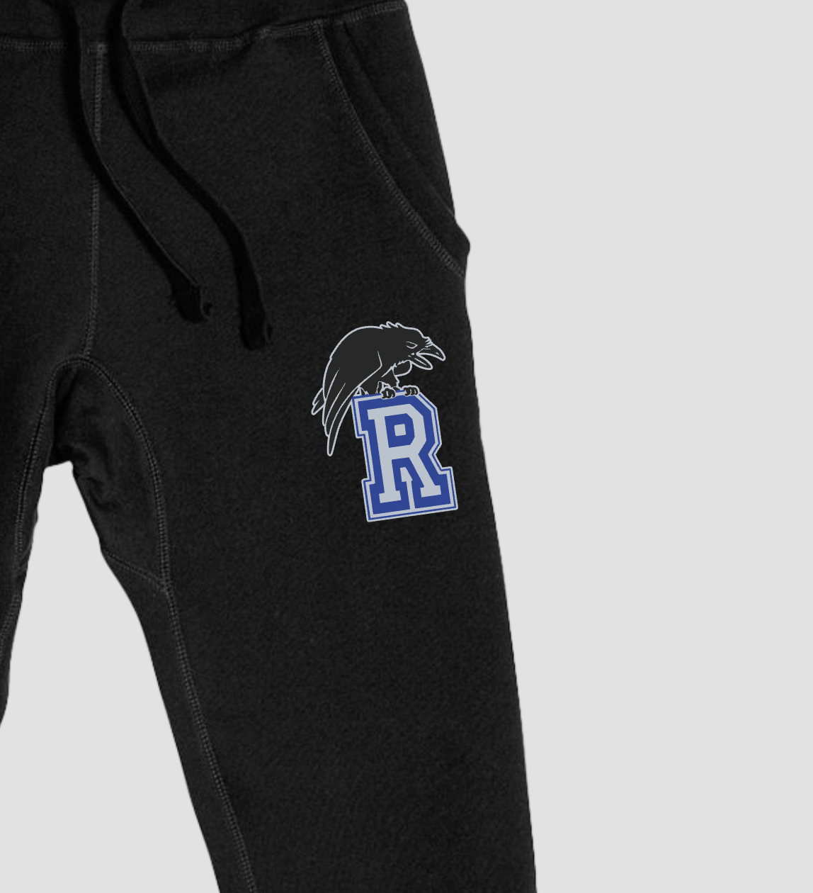 Black sweatpants with a logo on the leg against a light gray background