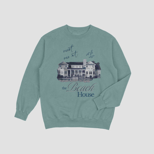 Teal sweatshirt with a graphic of a beach house and text on a light gray background