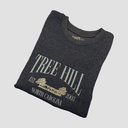 Folded dark gray sweatshirt with 'Tree Hill' text on a light gray background