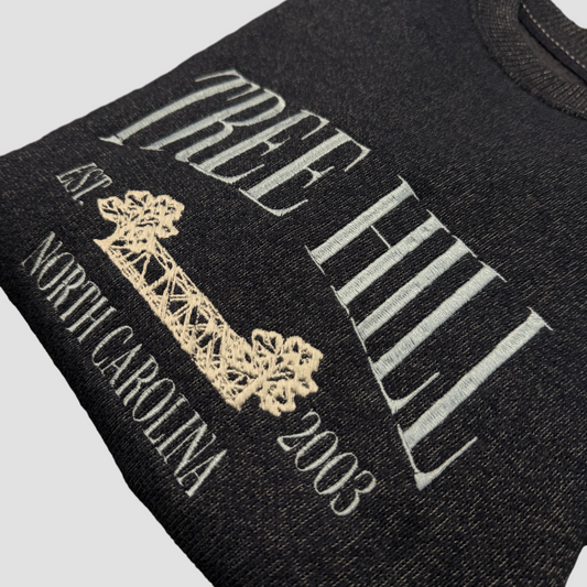 Black t-shirt with 'The Hill' branding and text on a light gray background